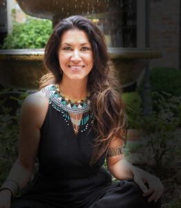 Mentoring Membership Program image of Evangeline in black dress sitting cross legged with fountain behind