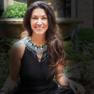 Mentoring Membership Program image of Evangeline in black dress sitting cross legged with fountain behind